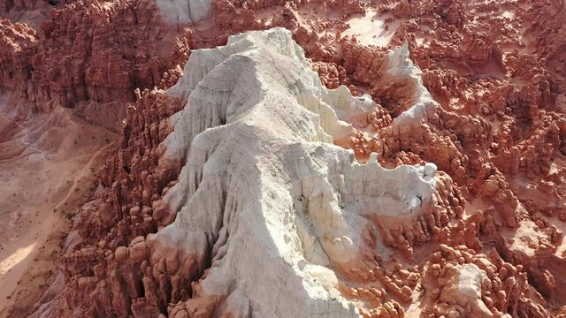 Aerial 4K view of strange red and white rock sandstone formation surrounded by hoodoos in rocky southwest desert landscape