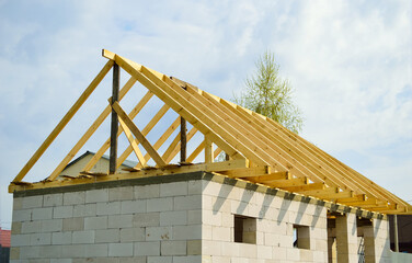 wooden frame of the future roof from wooden boards (beams and rafters) against the sky