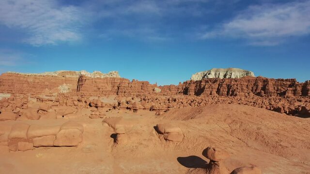 Dynamic aerial video of hoodoos and red rock formations dotting desert landscape in southwest United States. Drone footage filmed in Goblin Valley State Park, Utah.