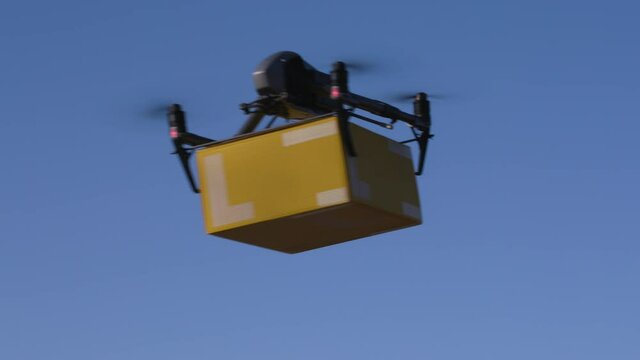 delivery drone carrying parcel flying across the blue sky