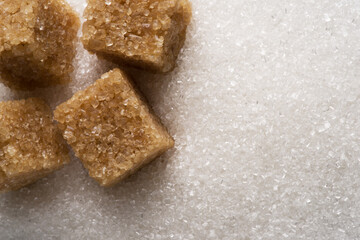 White refined sugar granules and brown sugar cubes close-up. Food background.