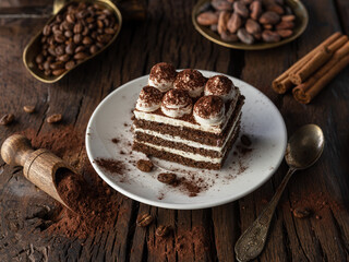 Slice of chocolate cake with tiramisu cream and cocoa powder on wooden table.