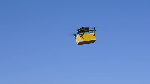 delivery drone carrying parcel flying across the blue sky