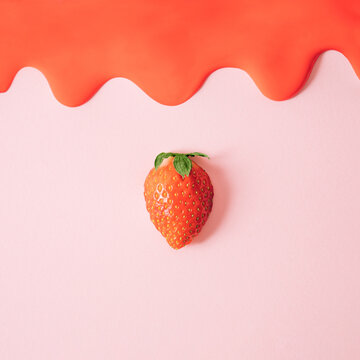 Fresh flat lay composition with single strawberry and red melting cream on pink background.