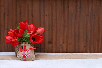 Holzhintergrund mit roten Tulpen und Herz.