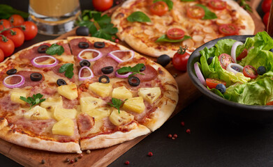 Family or friends having pizza party dinner. Flat-lay of people clinking glasses with drink over rustic dark stone table with various kinds of Italian pizza, top view. Fast food lunch, celebration