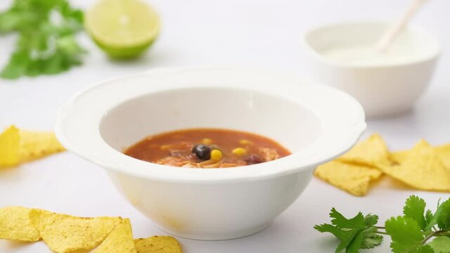 Pouring chicken enchilada soup from a ladle into a plate. Mexican food.