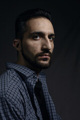Male portrait on a gray background. A man with a beard. Men's style. Natural male portrait. Man in a blue shirt