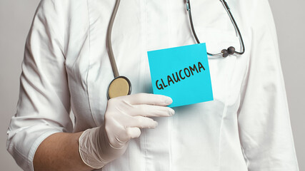 Cropped view of doctor in a white coat and sterile gloves holding a note with word - Glaucoma