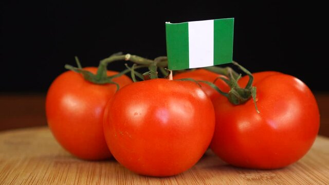 Man placing decorative toothpick with flag of Nigeria into bunch of tomatoes.