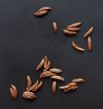 Close up of cumin seeds on a black background.