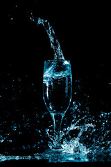 Splashes and drops of water in a glass are isolated on a black background.