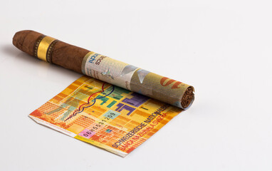 Cuban cigar on a rolled dollar on the white background stock photo
