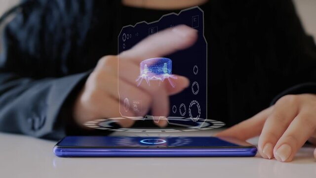Female hand interacts HUD hologram with robotic vacuum cleaner. Woman in black uses conceptual holographic technology of the future on the screen of a smartphone lying on a table