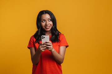 Obraz premium Young black happy woman smiling and using mobile phone