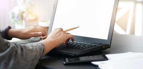 Focus on hand. young asian businesswoman holding pencil while she work at home with her computer laptop and smart phone