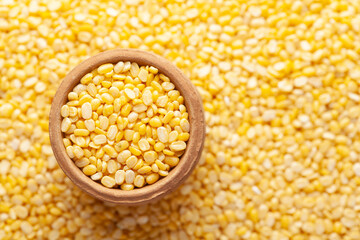 Macro Close-up of Organic yellow Gram (Vigna radiata) or split yellow moong dal in an earthen clay pot (kulhar) on the self background. Top view