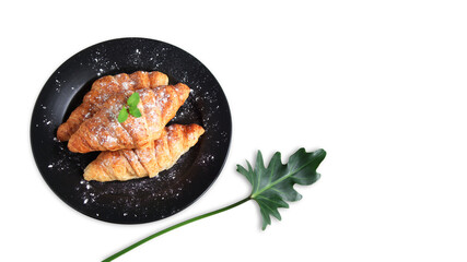 Croissants in black ceramic plate, Decorated with peppermint, icing and Philodendron Xanadu leaf, Isolated on white background with copy space, Bakery homemade from whole wheat and grains for healthy.