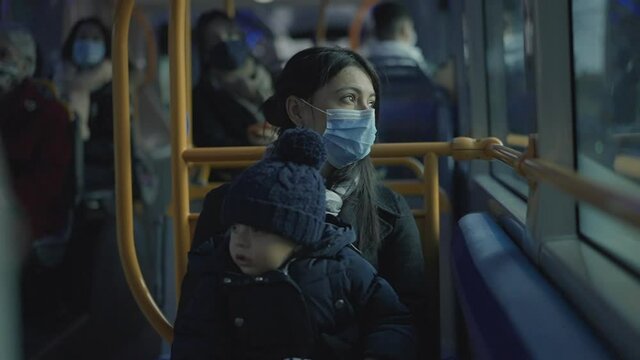 Mother riding bus with baby infant on lap during covid-19 face mask