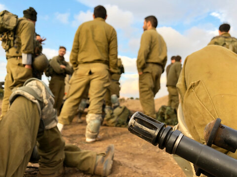 Israeli soldiers resting in IDF military training in the Golan Heights. Close up of Assault rifle M16. with Infantry combat soldiers in the background.  reserve service in the north of the Holyland,