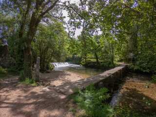 A beautiful little waterfall cascade and an old stone footbridge over the Neiva River in Antas, Esposende, Portugal.