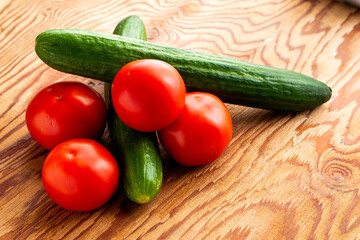 two cucumbers and four tomatoes on a wooden background