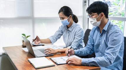 Two business colleagues brainstorming new ideas for business during looking financial data on laptop screen