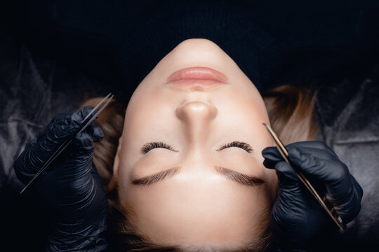 Eyelash extension procedure top view. Woman eye with beauty black lashes