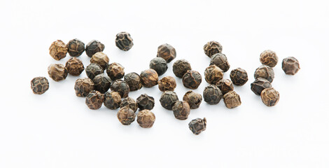 Dry seeds of black pepper on a white surface in close up.  Spice. Ingredients. Condiments.  