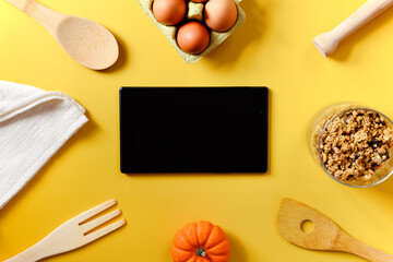 Flat lay with tablet with black mockup and place for text on yellow background. Food blogger's workplace. Culinary blog, recipe template, online cooking courses. Healthy food concept. Copy space.