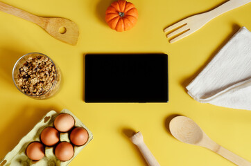 Flat lay with tablet with black mockup and place for text on yellow background. Food blogger's workplace. Culinary blog, recipe template, online cooking courses. Healthy food concept. Copy space.