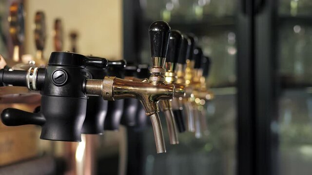A row of beer steel taps in a dark pub or bar. Taps for draught beer in a modern bar.