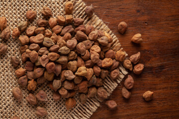 macro Close-up of Organic chana or chickpea (Cicer arietinum) or whole white Bengal gram dal cleaned on Jute mat and wooden top.