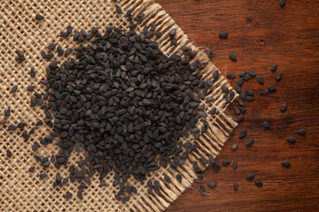 Macro Close up of Organic Black Sesame seeds(Sesamum indicum) or Black Til with the shell cleaned on Jute mat and wooden top.