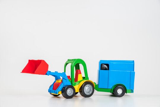 Children's toy plastic car isolated on white background. A multicolored excavator with a horse trailer.