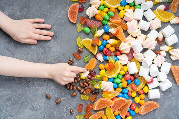 Children's hands reach for sweets lying on the table.