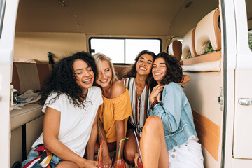 Happy young women sitting together in camper van enjoying vacation