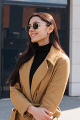 Fototapeta premium Stylish outdoor spring portrait. A woman in a coat and sunglasses