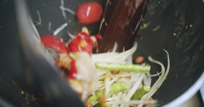 closeup cooking mixing spicy green papaya salad or Som Tam, Thai popular traditional street food