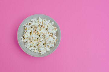 A bowl of popcorn on a pink copy space background.