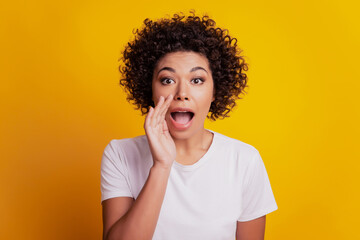 Funny beautiful woman palm open mouth scream look camera on yellow wall