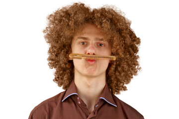A long-haired curly-haired guy in a brown shirt on a white background uses a wooden comb. Emotions...