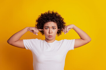 Picture of african student lady with fingers cover ears on yellow background