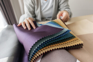 female designer with fabric color samples choosing textile for curtains