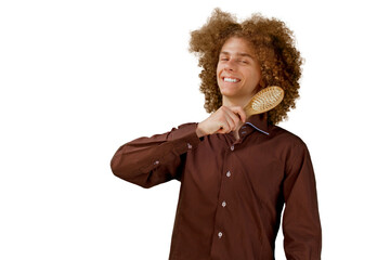 A long-haired curly-haired guy in a brown shirt on a white background uses a wooden comb. Emotions before a haircut in a hairdresser