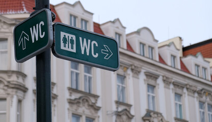 Obraz premium WC sign, logo of public toilets in the street against building background. For female, male. Public toilet sign against building.