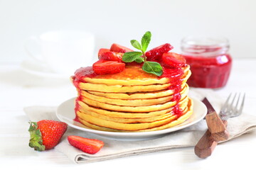 Pancakes with strawberries and mint on a white background