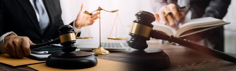 Justice and law concept.Male judge in a courtroom with the gavel, working with, computer and docking keyboard, eyeglasses, on table in morning light