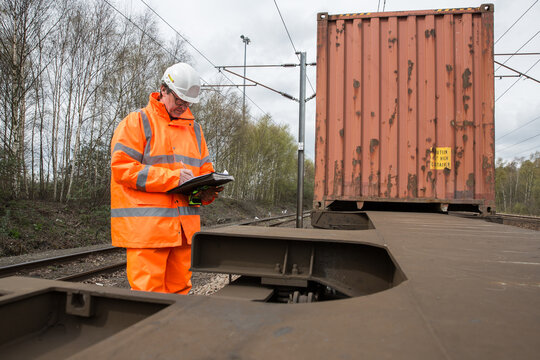 Railway Worker Inspecting A Shipping Container Train