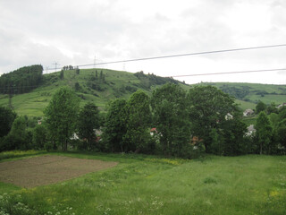 green forest in the mountains. Power lines in the mountains. Industrial background in the mountains. Scenic panoramic view on a cloudy day.